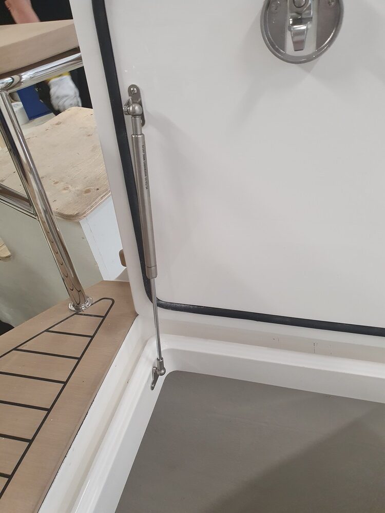 A stainless steel gas spring holding open a hatch in a boat.