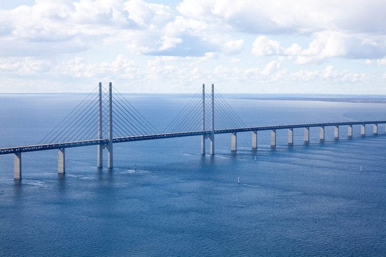 Long bridge over blue water and sky with white clouds