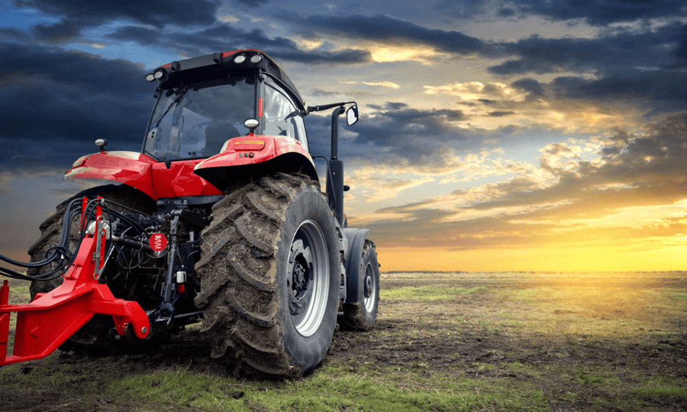 Red tractor infield with sunrising on the horizon