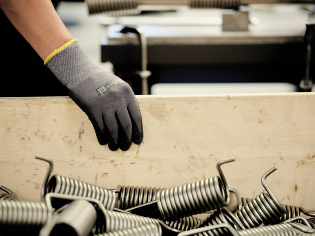 A close up shot of a hand wearing a glove carrying a thin wood panel.