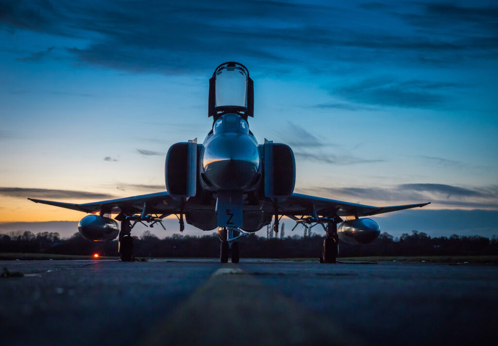 A defense jet that has landed on a runway, with a dark blue sunset sky in the background.